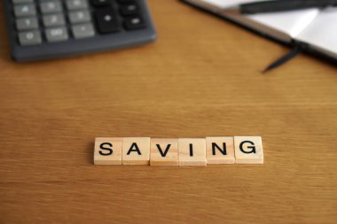 Kurtarıyorum. İş ve finansal kavramlar. Hesap makinesi ve arkaplanda not defteri olan tahta harflerle yazılmış sözcük