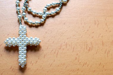 Katolik dini. Fotokopi alanı olan hafif ahşap zemin ve inci haçlı tespih.