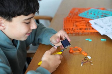 Ekransız boş zaman ve boş zaman. Manipülatif aktiviteler, iyi motor beceriler. Çocuk güneş paneli ve kablolarla model yapıyor.