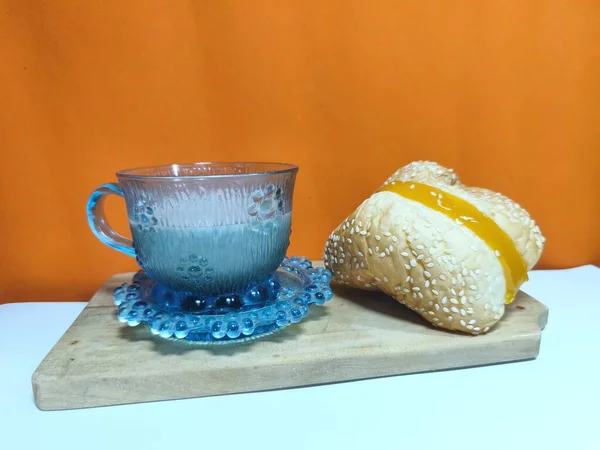 Bir fincan sıcak çikolata, ahşap bir tepside lezzetli buğulanmış ekmekle servis edilir. Bu düzen mutfak, ürün, konukseverlik ya da reklam fotoğrafçılığı için mükemmel. Uzayı kopyala Seçici odak.