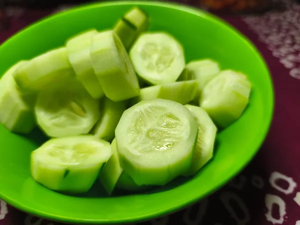 Yeşil bir kasede taze kesilmiş salatalıklar servis edilir. Mutfak, ürün, konukseverlik ya da reklam fotoğrafçılığı için mükemmel. Yakın plan. Uzayı kopyala Seçici odak.