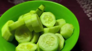 Yeşil bir kasede taze kesilmiş salatalıklar servis edilir. Yemek, ürün, konukseverlik ve reklam ortamlarında yemek sinematografisi için mükemmel. Yakın plan. Uzayı kopyala Seçici odak.