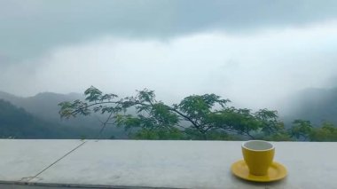 Yüksek bir yerdeki egzotik yemek yerinde, gözlerinizin önünde dağların ve sisli gökyüzünün manzarasıyla bir fincan sıcak içeceğin tadını çıkarıyorsunuz. Tumpeng Menoreh, Yogyakarta, Endonezya 'da yer alan bölge, büyüleyici bir doğal turizm beldesi..