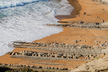 İspanya 'nın Cantabrian kıyısındaki Sable Sahili' nde eşsiz uçan kaya oluşumları ve altın kumun yüksek açılı görüntüsü.