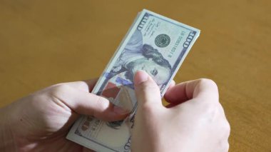 Bir el, Amerikan dolarlarını yarım daire şeklinde dağıtıp düz para birimi görüntüsü için yelpazesini yeniden yelpazeliyor. Geleneksel para yönetimi.