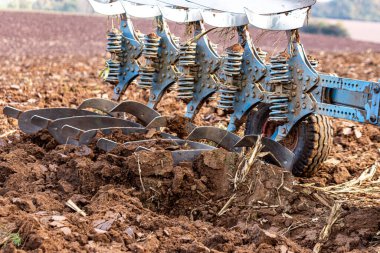 Büyük, modern bir traktör tarlayı sürerek toprağı ağır bir sabanla çevirir. Görüntü, güçlü tarım makinelerini, tarım arazilerini ve kırsal alandaki saha çalışmalarının başlangıcını gösteriyor..