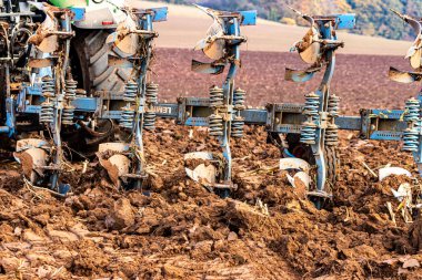 Büyük, modern bir traktör tarlayı sürerek toprağı ağır bir sabanla çevirir. Görüntü, güçlü tarım makinelerini, tarım arazilerini ve kırsal alandaki saha çalışmalarının başlangıcını gösteriyor..