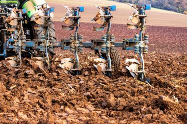 Büyük, modern bir traktör tarlayı sürerek toprağı ağır bir sabanla çevirir. Görüntü, güçlü tarım makinelerini, tarım arazilerini ve kırsal alandaki saha çalışmalarının başlangıcını gösteriyor..