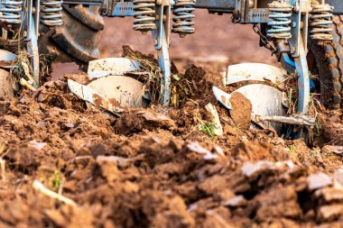 Büyük, modern bir traktör tarlayı sürerek toprağı ağır bir sabanla çevirir. Görüntü, güçlü tarım makinelerini, tarım arazilerini ve kırsal alandaki saha çalışmalarının başlangıcını gösteriyor..