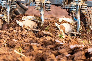 Büyük, modern bir traktör tarlayı sürerek toprağı ağır bir sabanla çevirir. Görüntü, güçlü tarım makinelerini, tarım arazilerini ve kırsal alandaki saha çalışmalarının başlangıcını gösteriyor..