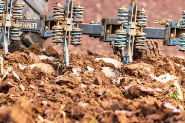 Büyük, modern bir traktör tarlayı sürerek toprağı ağır bir sabanla çevirir. Görüntü, güçlü tarım makinelerini, tarım arazilerini ve kırsal alandaki saha çalışmalarının başlangıcını gösteriyor..
