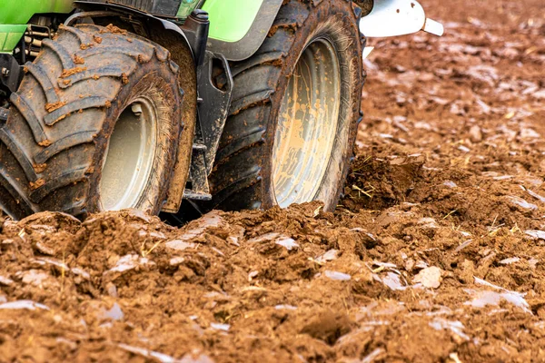 Büyük, modern bir traktör tarlayı sürerek toprağı ağır bir sabanla çevirir. Görüntü, güçlü tarım makinelerini, tarım arazilerini ve kırsal alandaki saha çalışmalarının başlangıcını gösteriyor..