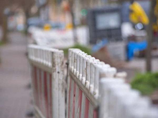 Trafik bariyerleri ve çalışma alanını koruyan uyarı levhaları olan yol inşaatı. Olay yerinde altyapı bakımı, araçlar için güvenlik önlemleri ve kentsel bir çevrede devam eden sokak onarım çalışmaları görülüyor..