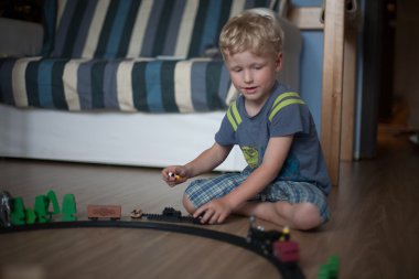 Çocuk demiryolu odada beyaz kıvırcık saçlı çocuk oynar