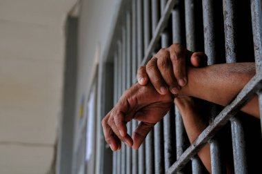 prisoner's hands behind bars