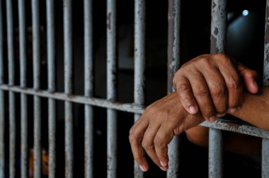 prisoner's hands behind bars