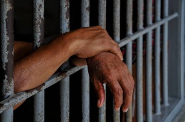 prisoner's hands behind bars