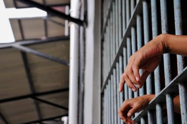 prisoner's hands behind bars