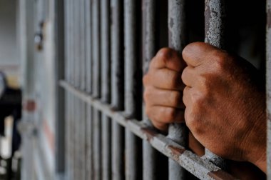 prisoner's hands behind bars