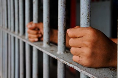 prisoner's hands behind bars