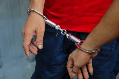  Siyah ve kırmızı giysiler giyen bir kişinin bilekleri ağır gümüş metal kelepçelerle birbirine bağlanır, kolluk kuvvetlerinin temalarını aktarır, cezai tutuklama, cezalandırma ve hukuki işlemler.