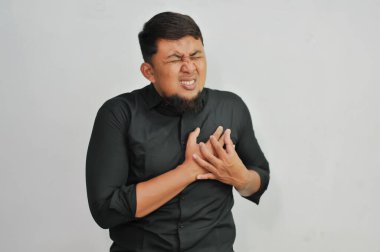 Siyah tişörtlü, kalp krizi geçiren, acı çeken Asyalı bir adamın portresi..