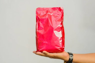 Beyaz arka planda kadın eli olan kırmızı çanta..