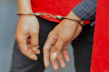 Mahkemeye götürülürken elleri kelepçeli bir mahkumun yakın çekimi. Kanun uygulama, adalet sistemi ve ceza davası kavramı.