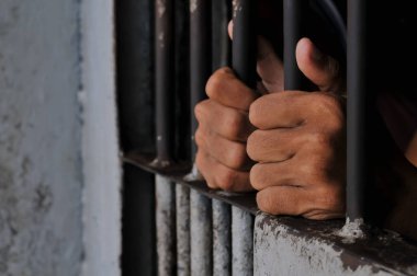 prisoner's hands behind bars