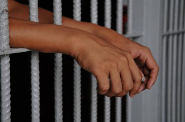prisoner's hands behind bars