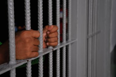 prisoner's hands behind bars