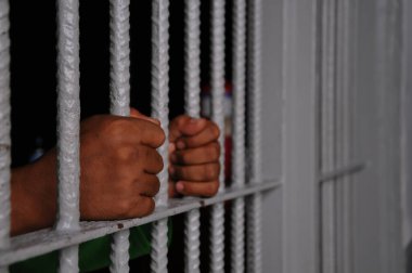 prisoner's hands behind bars