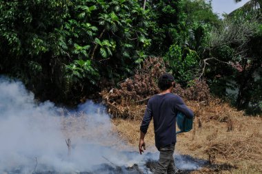 Riau-Endonezya, 20. Januari 2026: Gençler bahçeyi temizliyor ve çöpleri yakıyor