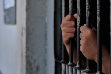 Mahkûmların elleri parmaklıklar ardında.