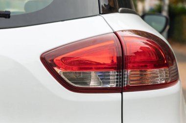 Beyaz bir yolcu vagonunun arka sağ tarafında far, tampon, dikiz aynası ve cam gibi büyük görüntüler var..