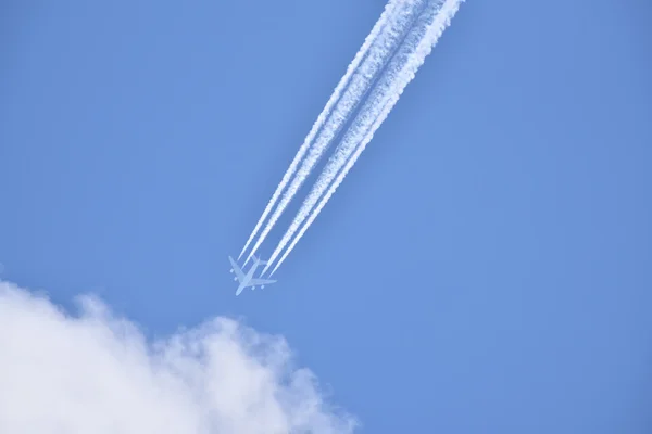 White airliner pulling white contrails in blue cloudy sky — Stock Photo, Image