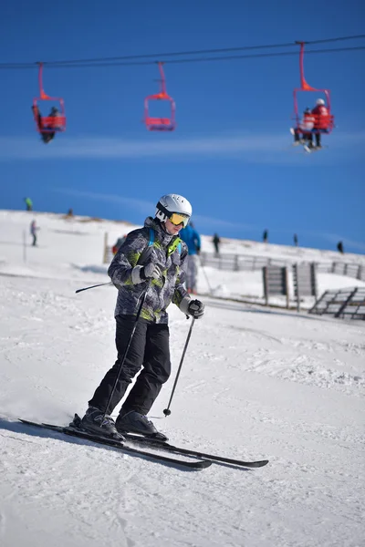 Ung man skidåkning slalom med blå himmel och stollift i bakgrunden — Stockfoto