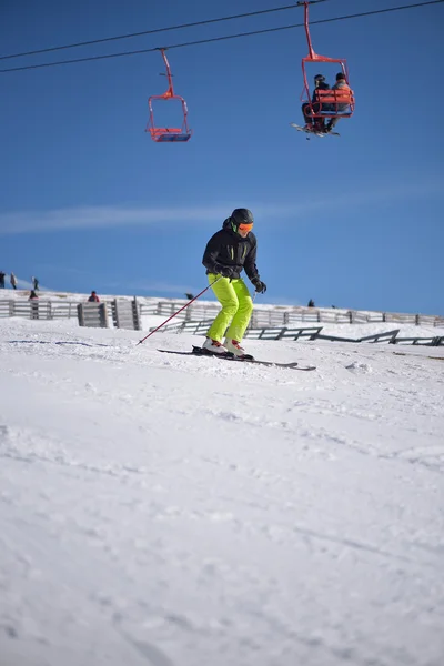 Skidåkare störtlopp på sluttning med blå himmel och chairlift — Stockfoto