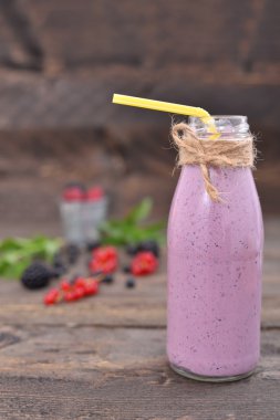 Milk shake çilek top ile bir şişe rustik bir tabloda güler yüzlü görüntülemek