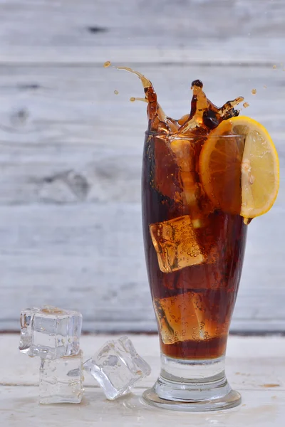 Citroen segment spatten in een vol cola en ijs kubussen glas — Stockfoto