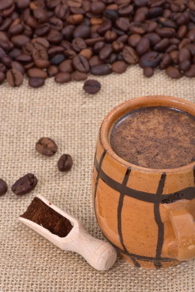 Vintage keramiska kopp med kaffe och mjölk på en jute med kaffebönor i bakgrunden — Stockfoto