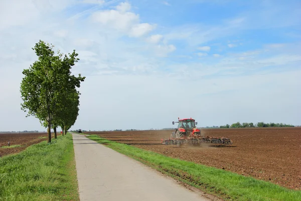 Tractor en una granja que trabaja con una grada de disco — Foto de Stock