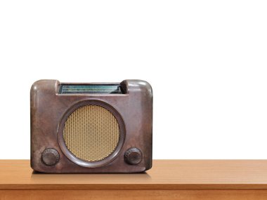 Antika kahverengi bir radyo, beyaz bir arka plana karşı ahşap bir masada oturur..