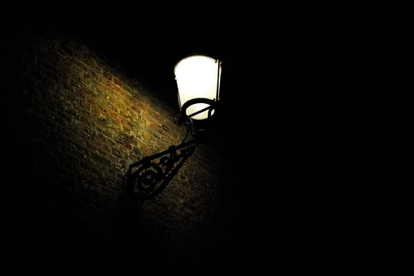 夜晚的路灯照亮了砖墙的一部分 — 图库照片