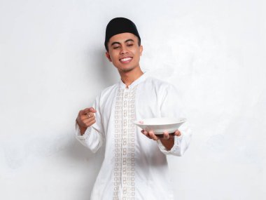 Genç Müslüman adam elinde tabak tutarken gülümsüyor..