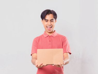 Neşeli Asyalı bir adam elinde karton bir paket kutusuyla dikiliyordu. Ekommerce teslimat konsepti için izole edilmişti..
