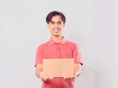 Neşeli Asyalı bir adam elinde karton bir paket kutusuyla dikiliyordu. Ekommerce teslimat konsepti için izole edilmişti..