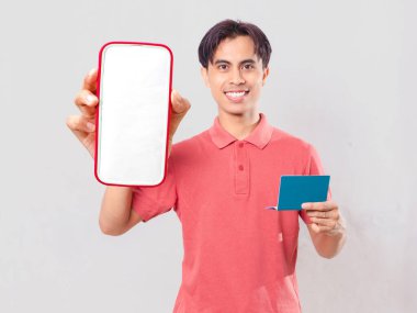 Dijital bankacılık ve finansal uygulama tanıtımı için izole edilmiş boş akıllı telefon ekranı gösteren neşeli Asyalı genç bir adam..