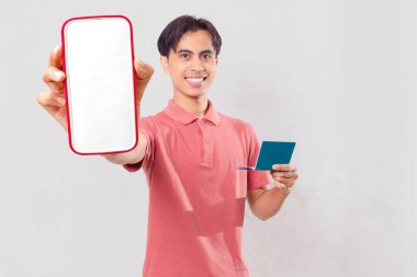 Dijital bankacılık ve finansal uygulama tanıtımı için izole edilmiş boş akıllı telefon ekranı gösteren neşeli Asyalı genç bir adam..