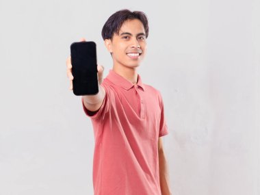 Gülümseyen, kendine güvenen genç Asyalı adam boş bir cep telefonu ekranı gösteriyor.
